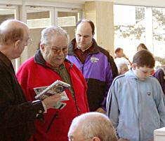 Long-time KSFF donor James P. Erickson from Wichita (in red) discusses his purchases with fellow attendees.