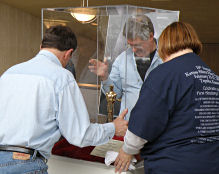Karl and Bill help Denise lower the top onto the display case.
