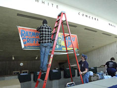 Trevor hangs the banner while Larry steadies the ladder