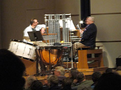 Marvin Faulwell plays an overature while Karl Mischler, on stage to run a DVD, listens