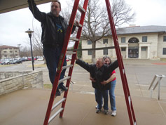 Brian Sanders climbs the ladder while Larry and Sue steady it