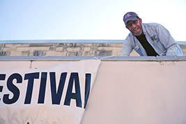 Karl Mischler smiles as he ties down one edge of the festival banner.