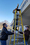 Brian Sanders and J.B. Kaufman hold the ladder steady as Karl Mischler climbs to the top with our Kansas Silent Film Festival banner, rolled-up.