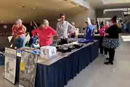 Several volunteers, all behind the desk, offer help to attendees who'd like to purchase silent film objects