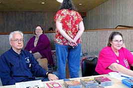 (Need name), Denise Morrison, Susan Rapsis and Jane Bartholomew are grouped behind the Sales-Table in the lobby